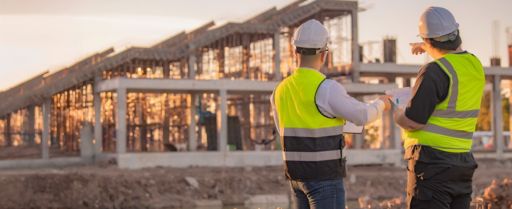 two construction workers look out at a building project